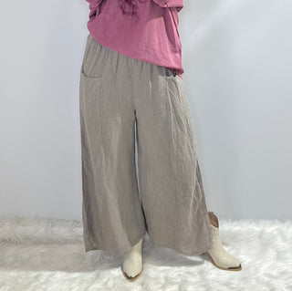 Gray oversized linen pants with wide legs, side slit panels, large front patch pockets and an elastic waistband