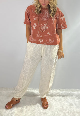 Women's Rust and Sage western graphic cropped tee with cowboy boots, hats, horseshoe and cactus print