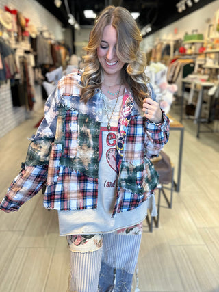 Handcrafted reversible patchwork flannel jacket with quilt inspired panels in blue, red, and earth tones with zigzag stitching, inside features a paisley pattern