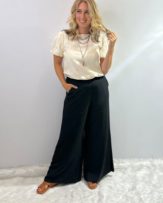 Womens black wide leg trouser pants with an elastic waistband featuring a relaxed fit and flowy silhouette for a sleek, comfortable look. 