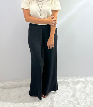 Womens black wide leg trouser pants with an elastic waistband featuring a relaxed fit and flowy silhouette for a sleek, comfortable look. 