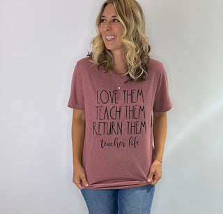Mauve pink graphic t shirt with the phrase love them, teach them, return them. Teacher Life in black bold lettering