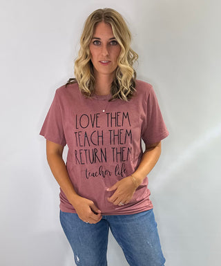 Mauve pink graphic t shirt with the phrase love them, teach them, return them. Teacher Life in black bold lettering