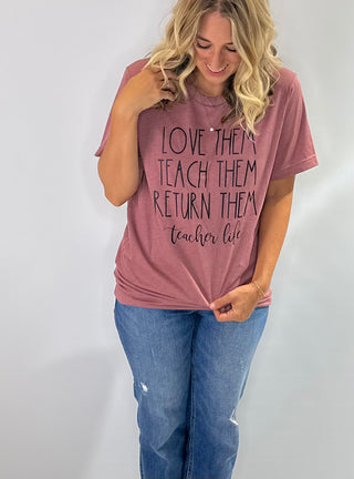 Mauve pink graphic t shirt with the phrase love them, teach them, return them. Teacher Life in black bold lettering