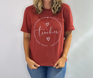 Teacher graphic tee, crimson with white lettering and circular text reading good, blessed, strong, beautiful, fierce, loving, caring, inspiring and heart accents