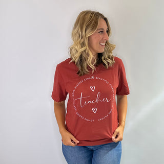 Teacher graphic tee, crimson with white lettering and circular text reading good, blessed, strong, beautiful, fierce, loving, caring, inspiring and heart accents