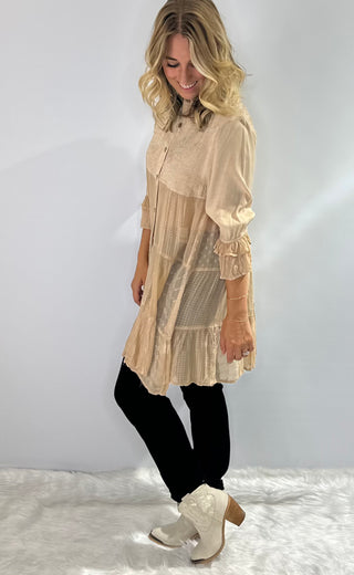 Long flowy blouse with a tiered patchwork design, translucent bodice, 3/4 ruffle sleeves, embroidered and jacquard details and a button front with collar in a soft beige. 