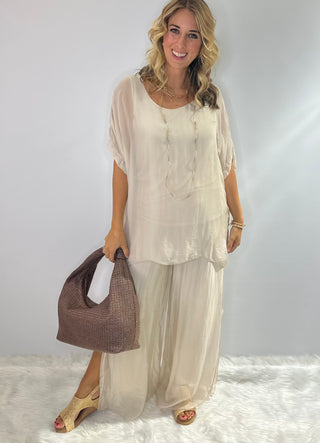 Oversized cream silk blouse with short sleeves, scoop neck, double-layer front and tie-back detail.