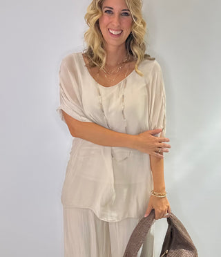 Oversized cream silk blouse with short sleeves, scoop neck, double-layer front and tie-back detail.