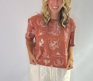 Women's Rust and Sage western graphic cropped tee with cowboy boots, hats, horseshoe and cactus print
