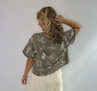 Women's Rust and Sage western graphic cropped tee with cowboy boots, hats, horseshoe and cactus print