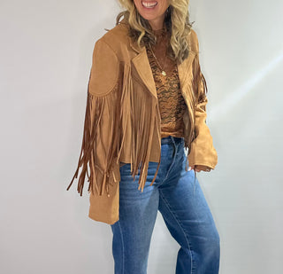 Stylish camel-colored suede jacket with long sleeves, a classic collar, and fringe detailing along the hem and sleeves. Perfect for adding a boho chic touch to any outfit