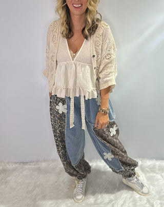 Pol Elastic waist patchwork jogger pants with drawstrings, paisley and leopard prints, and crochet daisy patch details in browns and denim blue. 