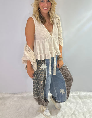Pol Elastic waist patchwork jogger pants with drawstrings, paisley and leopard prints, and crochet daisy patch details in browns and denim blue. 