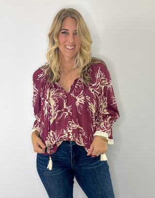 Floral printed 3/4 sleeve top with V-neck tassel tie, flutter lace trim sleeves, and flutter hem in olive/cream or burgundy/cream