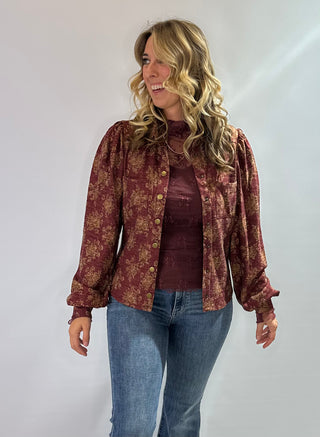 Burgundy knit top with gold floral pattern, vintage snap buttons, puff sleeves, and collar