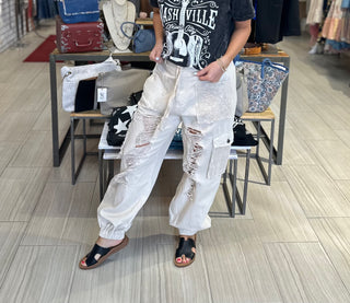 Cream jogger style pants with cargo pockets, crochet and distressed detail giving boho vibes