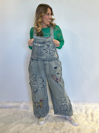 Flower Patchwork And Embroidered Denim Overalls with full length silhouette, adjustable button shoulder straps, side button closures, and functional bib pockets