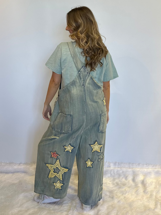 Star and Peace Patchwork denim bib overalls with oversized fit, adjustable button straps, side button closures, front bib pocket and full length silhouette