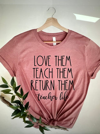 Mauve pink graphic t shirt with the phrase love them, teach them, return them. Teacher Life in black bold lettering