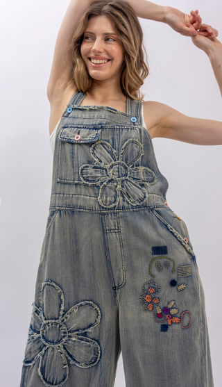 Flower Patchwork And Embroidered Denim Overalls with full length silhouette, adjustable button shoulder straps, side button closures, and functional bib pockets