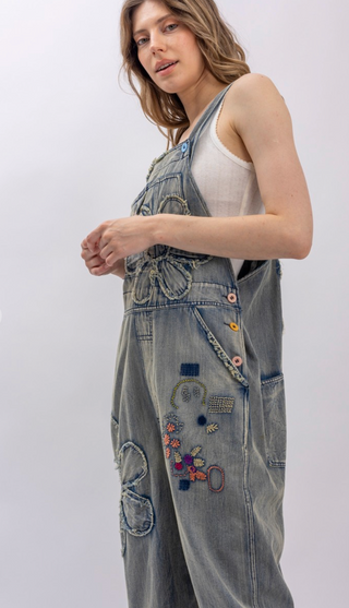 Flower Patchwork And Embroidered Denim Overalls with full length silhouette, adjustable button shoulder straps, side button closures, and functional bib pockets
