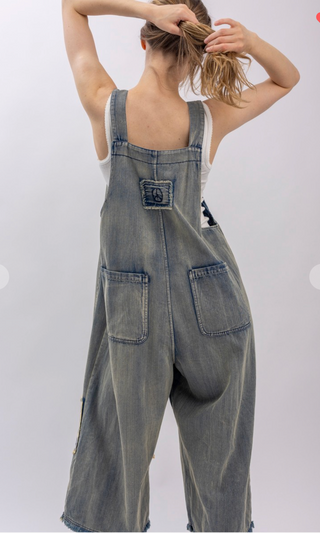 Mineral wash patchwork denim bib overalls with wide leg silhouette, adjustable shoulder straps, midi length, bib pocket and side pockets