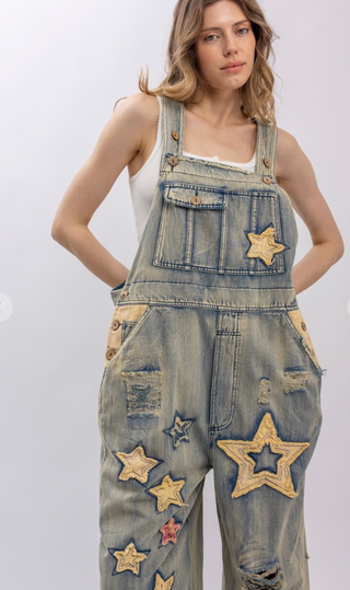 Star and Peace Patchwork denim bib overalls with oversized fit, adjustable button straps, side button closures, front bib pocket and full length silhouette