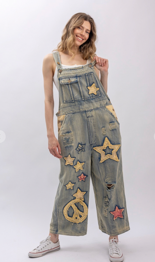 Star and Peace Patchwork denim bib overalls with oversized fit, adjustable button straps, side button closures, front bib pocket and full length silhouette