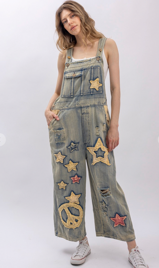 Star and Peace Patchwork denim bib overalls with oversized fit, adjustable button straps, side button closures, front bib pocket and full length silhouette
