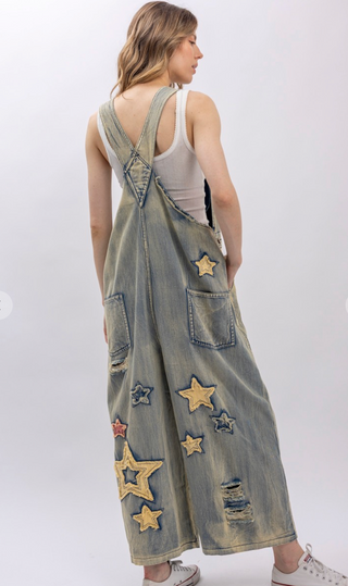 Star and Peace Patchwork denim bib overalls with oversized fit, adjustable button straps, side button closures, front bib pocket and full length silhouette